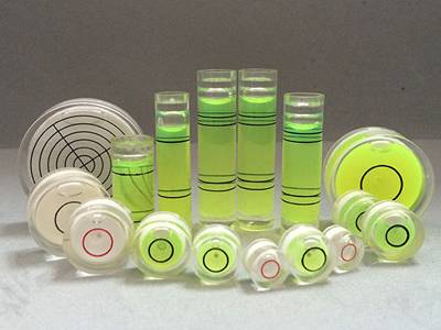 There are several tubular and circular glass bubble level vials on the ground.